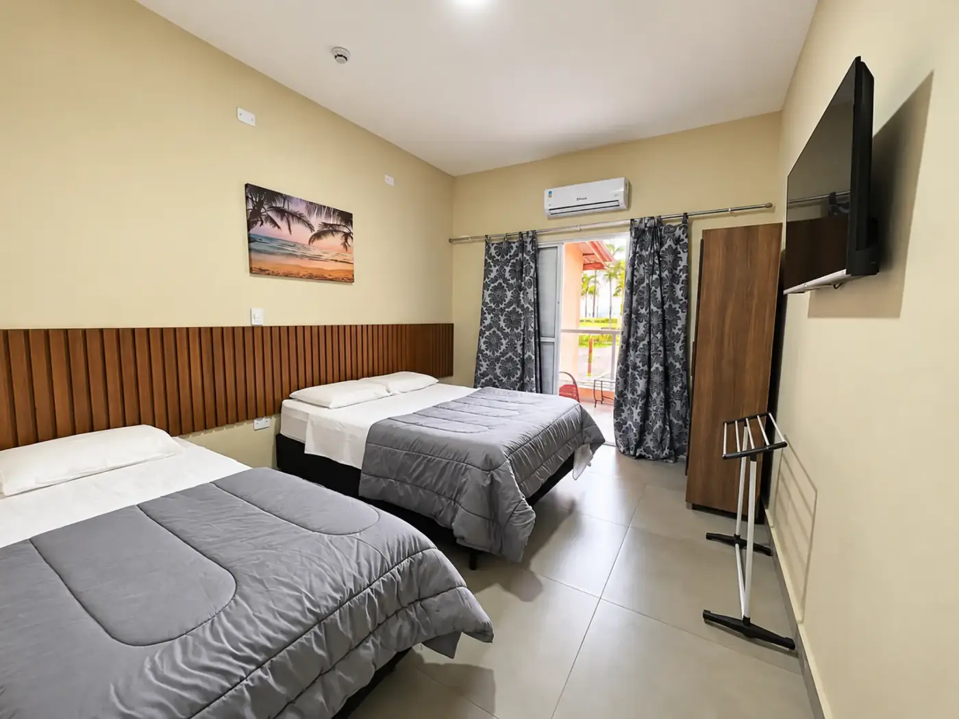 Quarto com camas de solteiro e casal e acesso à varanda